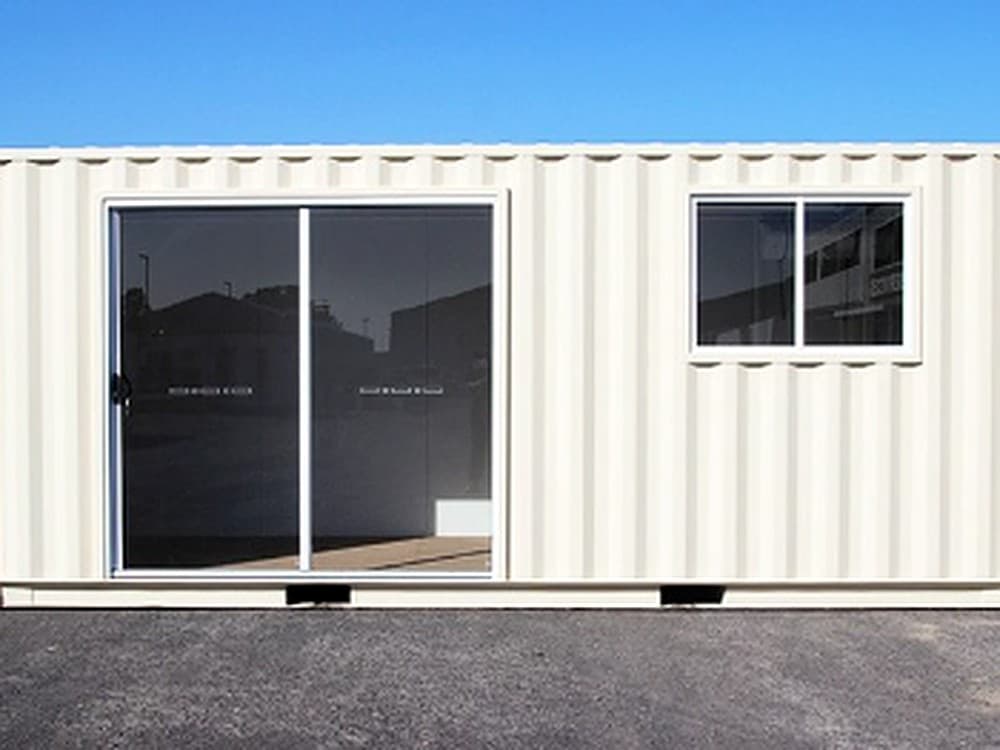 Converted shipping container with a sliding glass door and window used as a site office